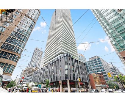 A tall building with a curved facade stands in the middle of a bustling city street.