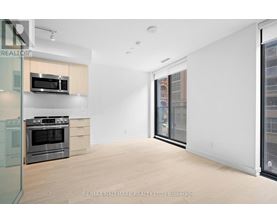 A spacious, empty room with a stove and microwave in a modern apartment.