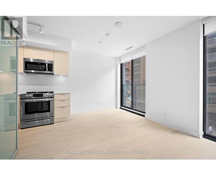 A spacious, empty room with a stove and microwave in a modern apartment.