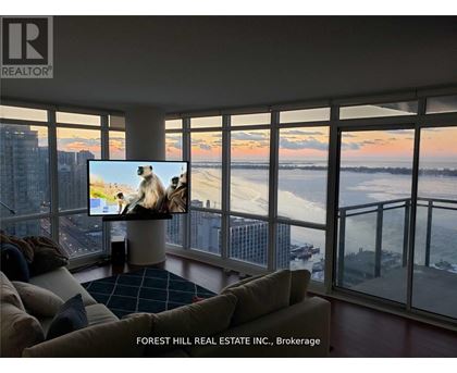 A living room with a large screen TV and a view of the city.