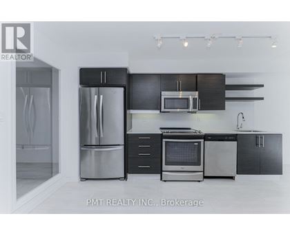 A modern kitchen with a stainless steel refrigerator and black cabinets.