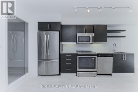 A modern kitchen with a stainless steel refrigerator and black cabinets.