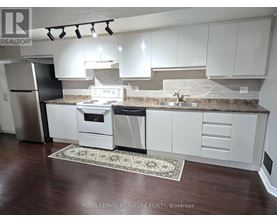 A kitchen with white cabinets and a black refrigerator.