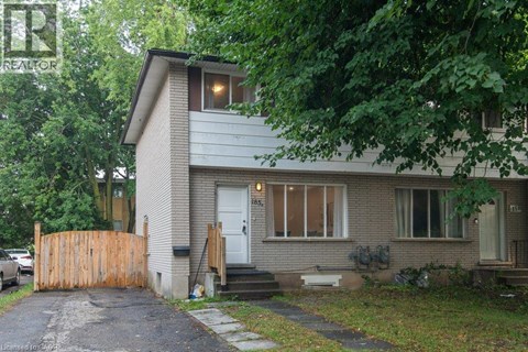 A house with a grey roof and a white door is surrounded by trees.
