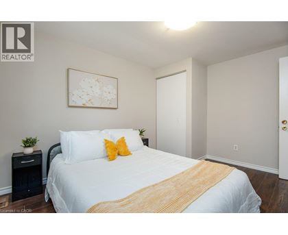 A bedroom with a white bed and a yellow throw blanket.