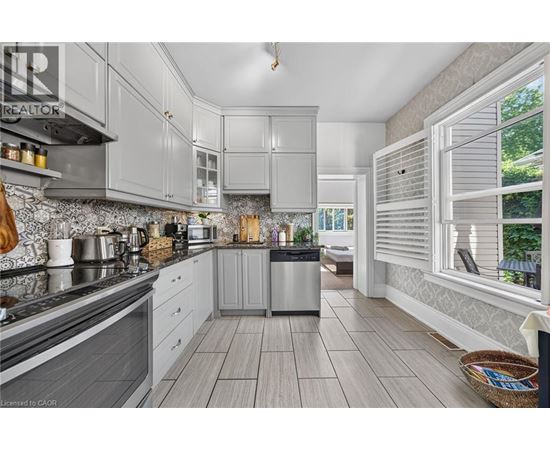 A modern kitchen with grey cabinets and a wooden floor.