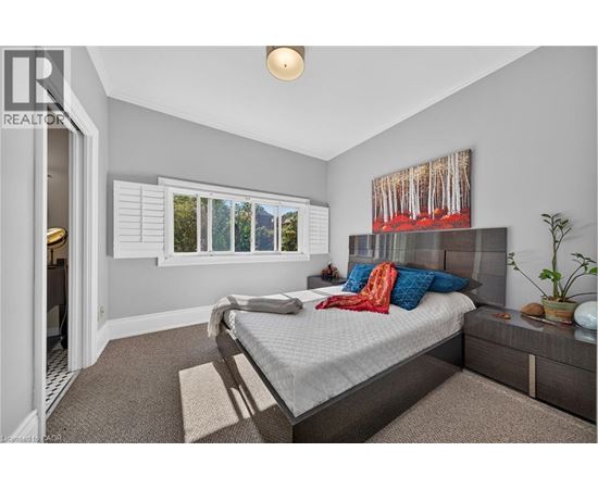 A bedroom with a bed, a nightstand, and a window with blinds.