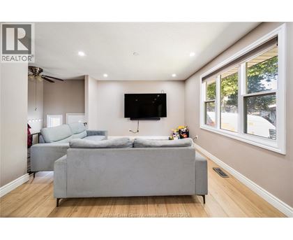 A living room with a grey couch and a flat screen TV mounted on the wall.