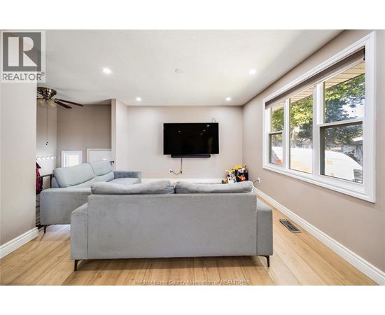 A living room with a grey couch and a flat screen TV mounted on the wall.