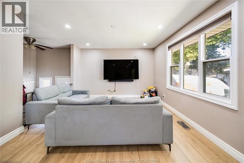 A living room with a grey couch and a flat screen TV mounted on the wall.