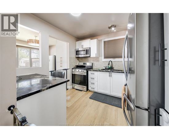 A kitchen with white cabinets and a black counter top.