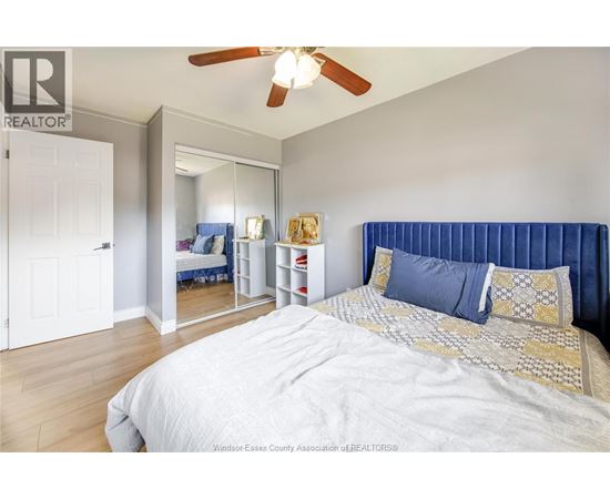 A bedroom with a large bed and a ceiling fan.