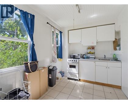 A kitchen with white cabinets and a black trash can.