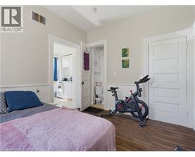 A bedroom with a bed, a pink blanket, a bicycle, and a doorway leading to another room.