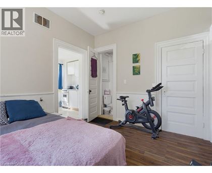 A bedroom with a bed, a pink blanket, a bicycle, and a doorway leading to another room.