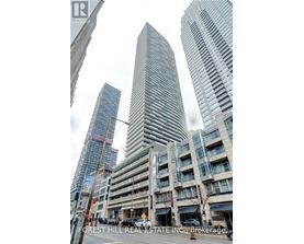 A tall building with a curved facade stands in front of two other buildings.