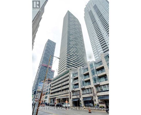 A tall building with a curved facade stands in front of two other buildings.