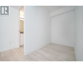 A white room with a wooden floor and a doorway leading to another room.