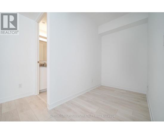 A white room with a wooden floor and a doorway leading to another room.