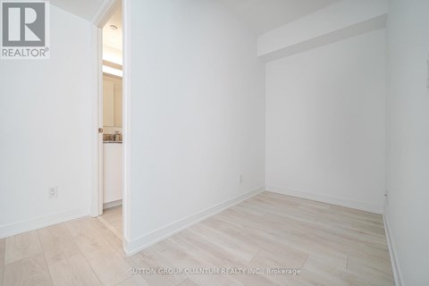 A white room with a wooden floor and a doorway leading to another room.