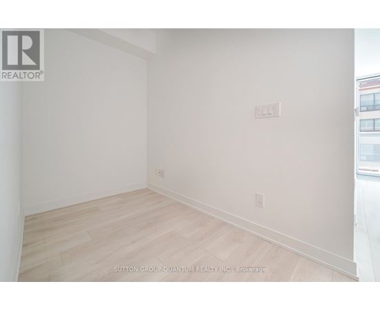 A room with white walls and wooden flooring, with a logo in the top left corner.