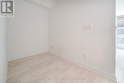 A room with white walls and wooden flooring, with a logo in the top left corner.