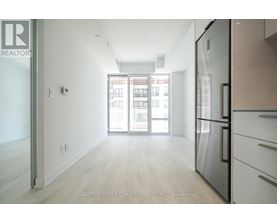 A kitchen with a refrigerator and a view of a building outside.