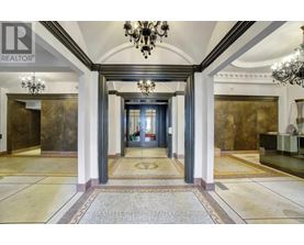 A hallway with a chandelier and a carpeted floor.
