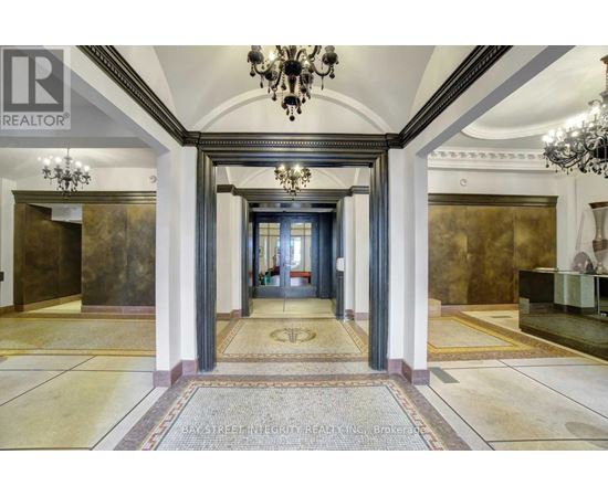 A hallway with a chandelier and a carpeted floor.