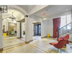 A spacious hallway with a red chair and a chandelier.