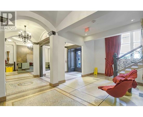 A spacious hallway with a red chair and a chandelier.