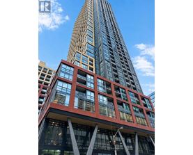 A tall building with a red and black facade is in the foreground with a blue sky in the background.
