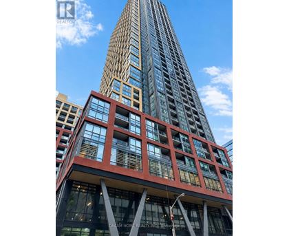 A tall building with a red and black facade is in the foreground with a blue sky in the background.