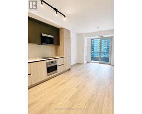 A modern kitchen with wooden floors and a large window.