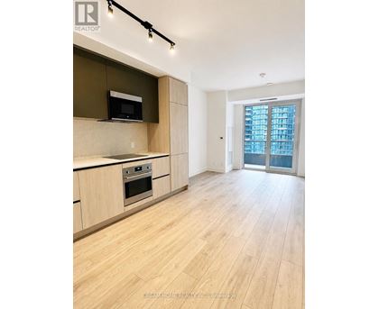 A modern kitchen with wooden floors and a large window.
