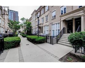 A row of townhouses with a sidewalk in front.