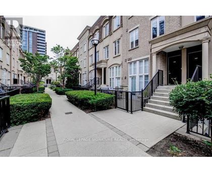 A row of townhouses with a sidewalk in front.