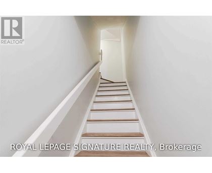 A white hallway with a staircase and a logo for Royal LePage Signature Realty in Brokerage.
