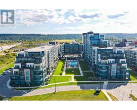 A large, modern apartment complex with a pool in the center, surrounded by greenery and a clear sky.