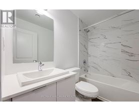 A white bathroom with a marble shower wall.