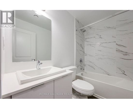 A white bathroom with a marble shower wall.