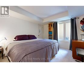 A bedroom with a bed, nightstand, and window with curtains.