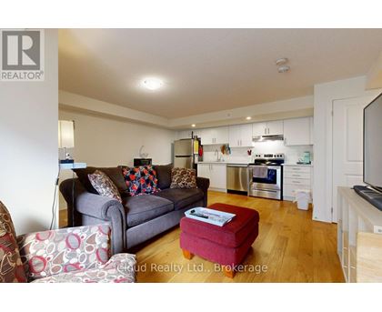 A living room with a grey couch and a red ottoman.