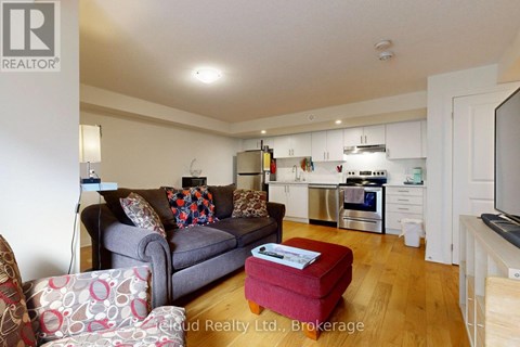 A living room with a grey couch and a red ottoman.