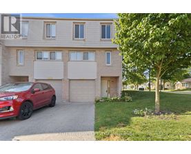 A red car is parked in front of a two-story building with a garage.