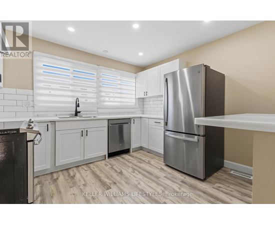 A modern kitchen with a stainless steel refrigerator and white cabinets.
