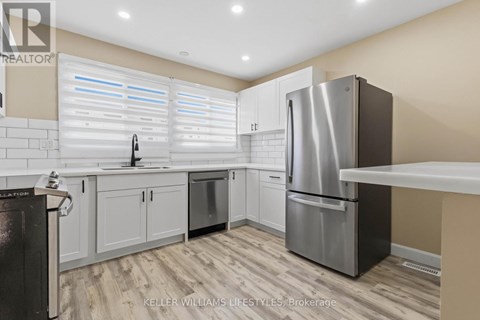 A modern kitchen with a stainless steel refrigerator and white cabinets.