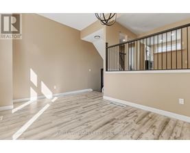 A spacious room with wooden flooring and a staircase leading to another room.