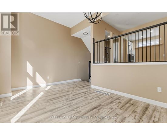 A spacious room with wooden flooring and a staircase leading to another room.