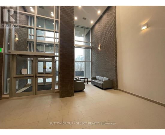 A hallway with a glass door and a brick pillar.